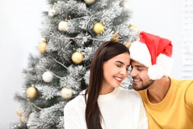 Happy young couple near Christmas tree at home