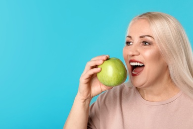 Photo of Smiling woman with perfect teeth and green apple on color background. Space for text