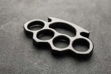 Photo of Brass knuckles on black stone background, closeup