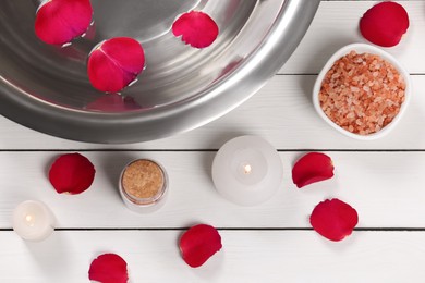 Photo of Flat lay composition with bowl of water and rose petals on white wooden table. Pedicure procedure