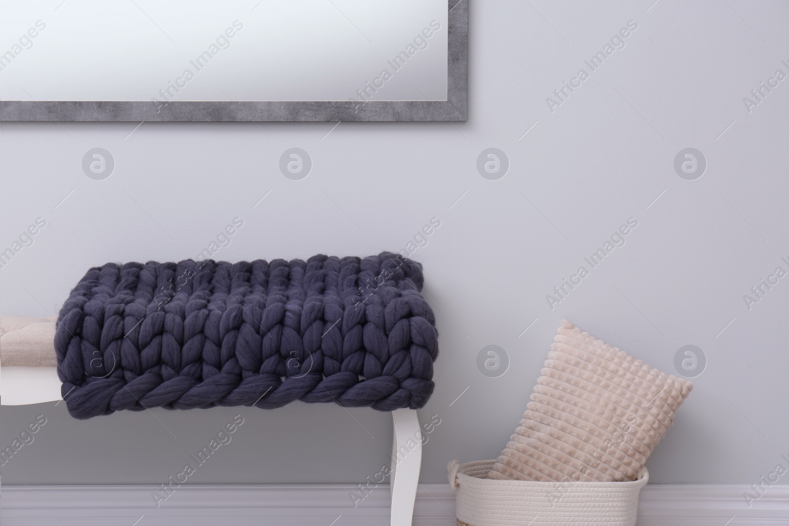 Photo of Knitted merino wool plaid on bench near grey wall