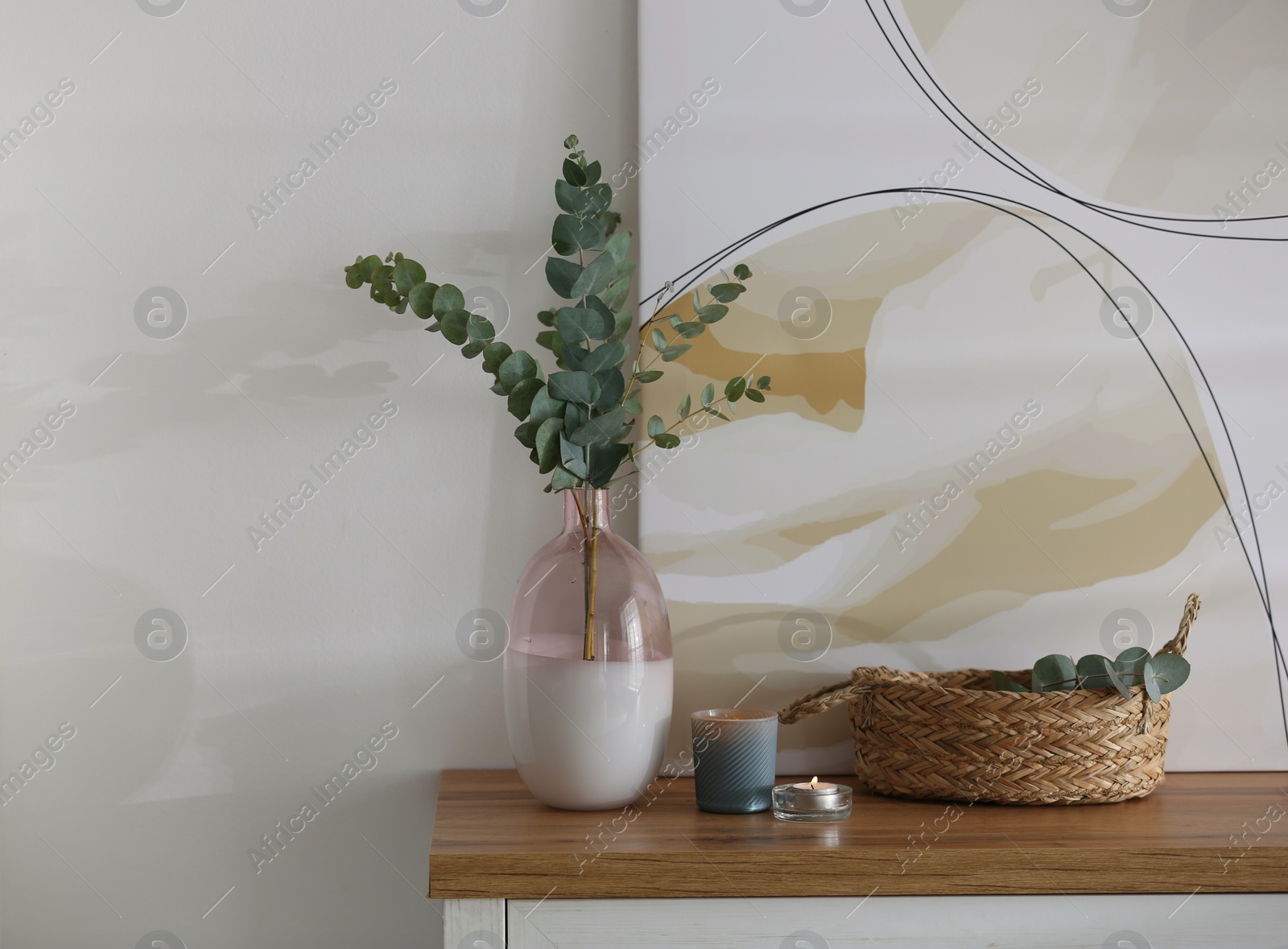 Photo of Vase with fresh eucalyptus branches on cabinet in room. Interior design