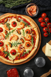 Photo of Delicious seafood pizza on black table, flat lay