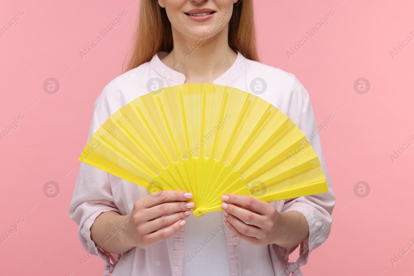 Photo of Woman with yellow hand fan on pink background, closeup