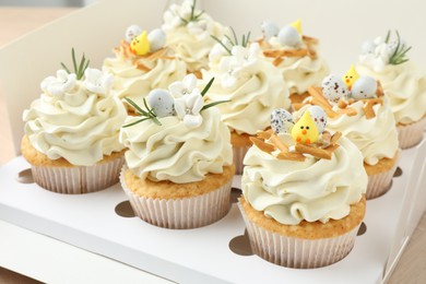 Photo of Tasty Easter cupcakes with vanilla cream in box, closeup