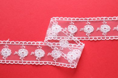 Photo of White lace on red background, top view