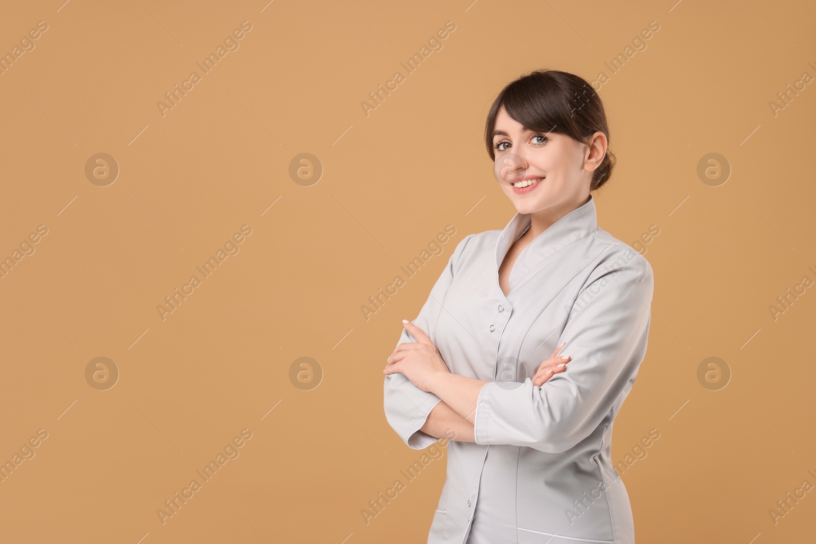 Photo of Cosmetologist in medical uniform on beige background, space for text