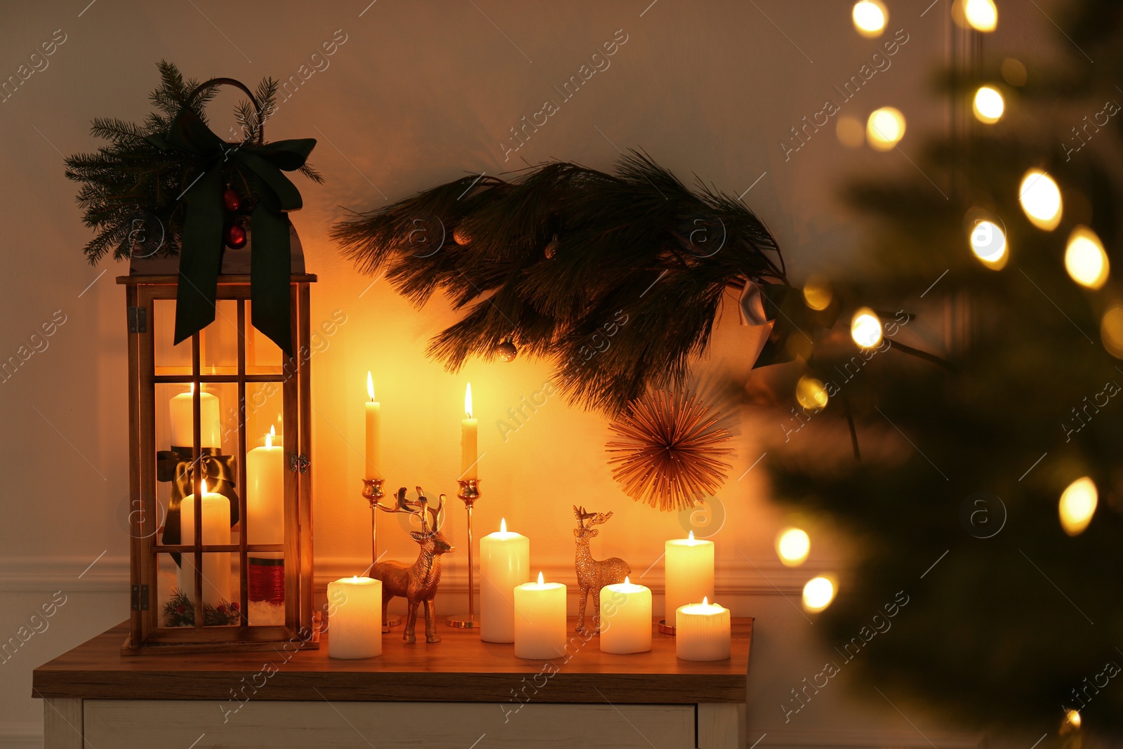 Photo of Wooden decorative Christmas lantern and burning candles on table indoors