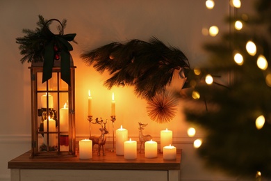 Wooden decorative Christmas lantern and burning candles on table indoors