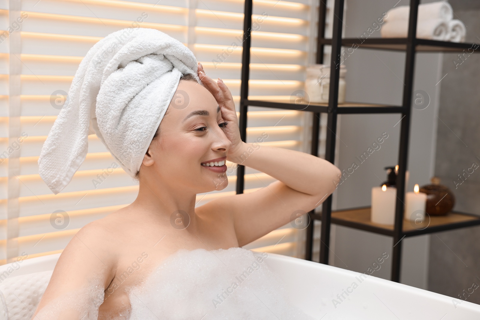 Photo of Happy woman taking bath with foam in tub indoors