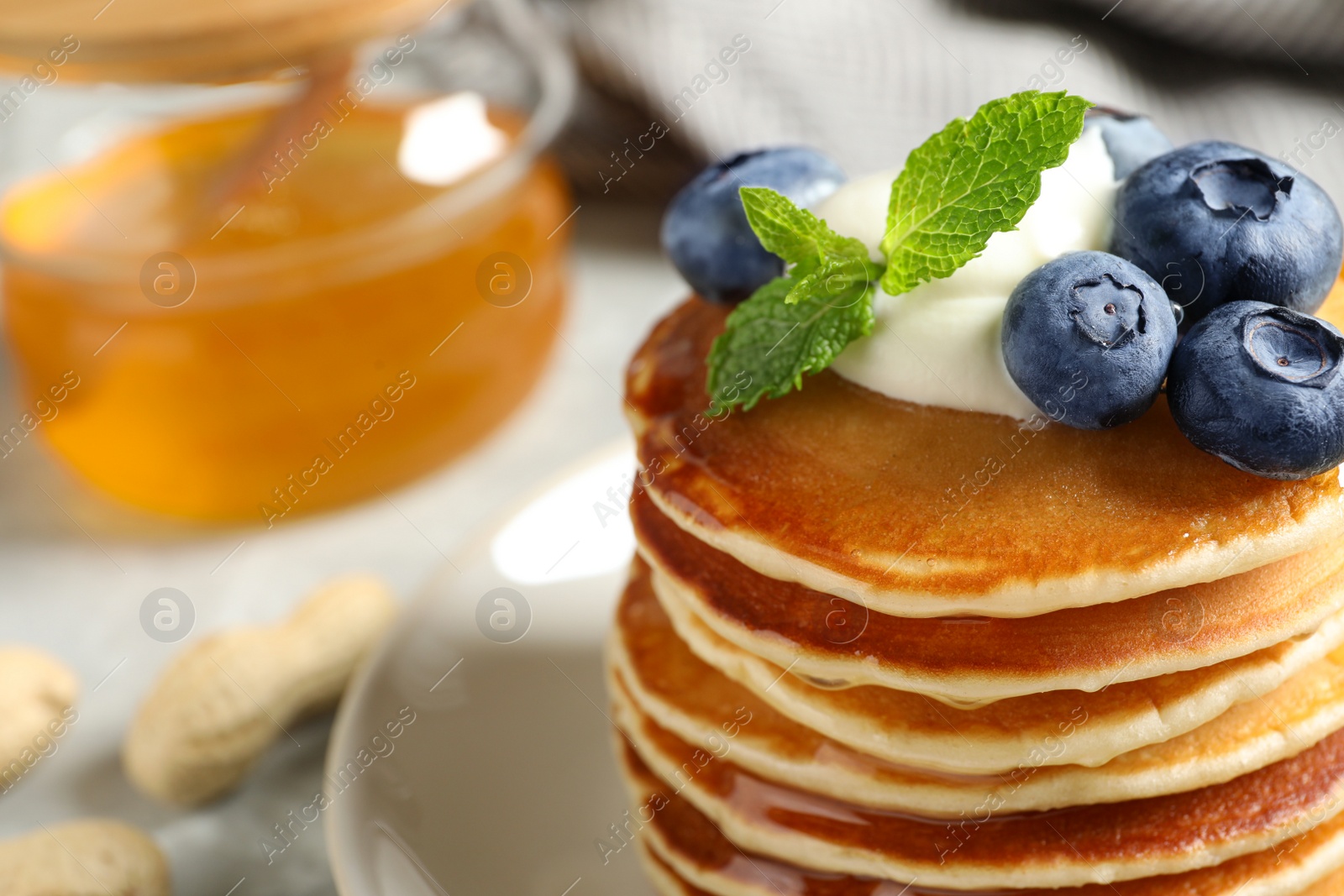 Photo of Plate of tasty pancakes with blueberries, sauce and mint on table, closeup