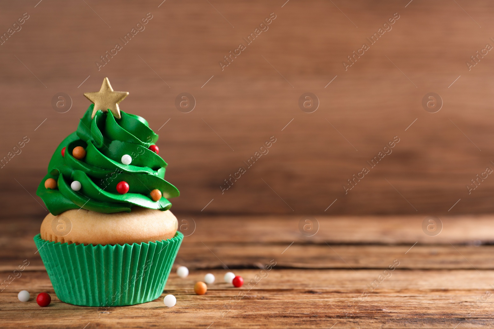 Photo of Christmas tree shaped cupcake on wooden table. Space for text