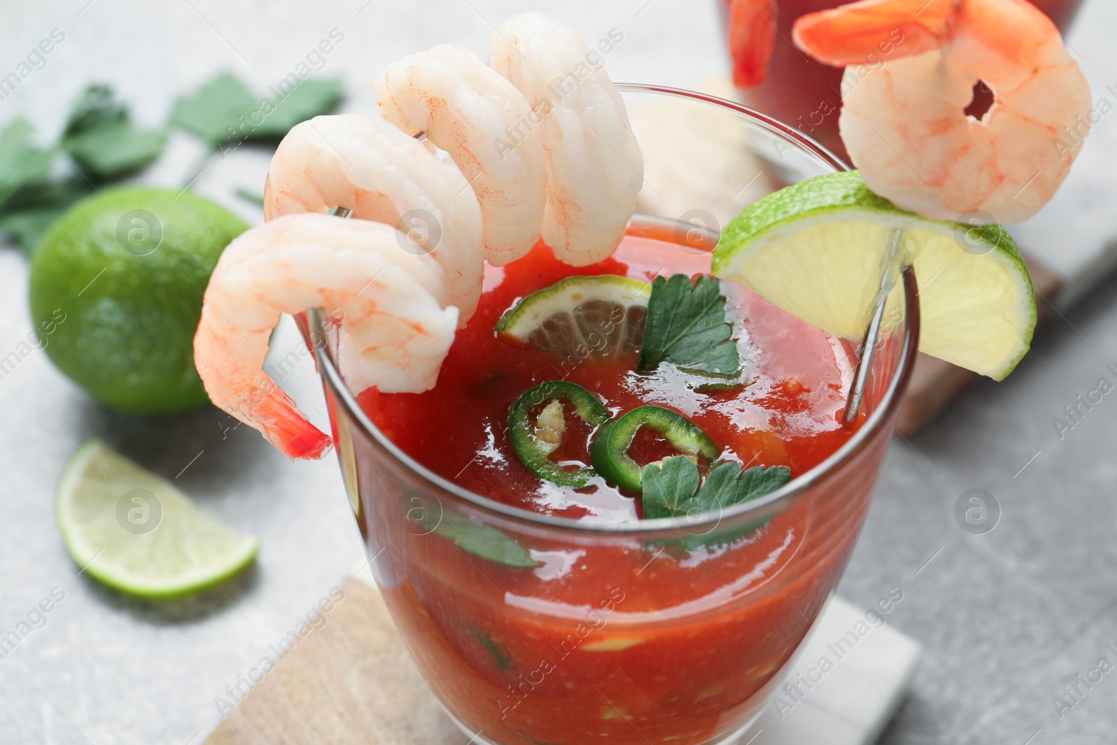 Photo of Tasty shrimp cocktail with sauce in glasses and lime on light table, closeup