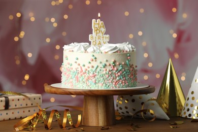 Photo of Beautiful birthday cake with burning candle and decor on wooden table