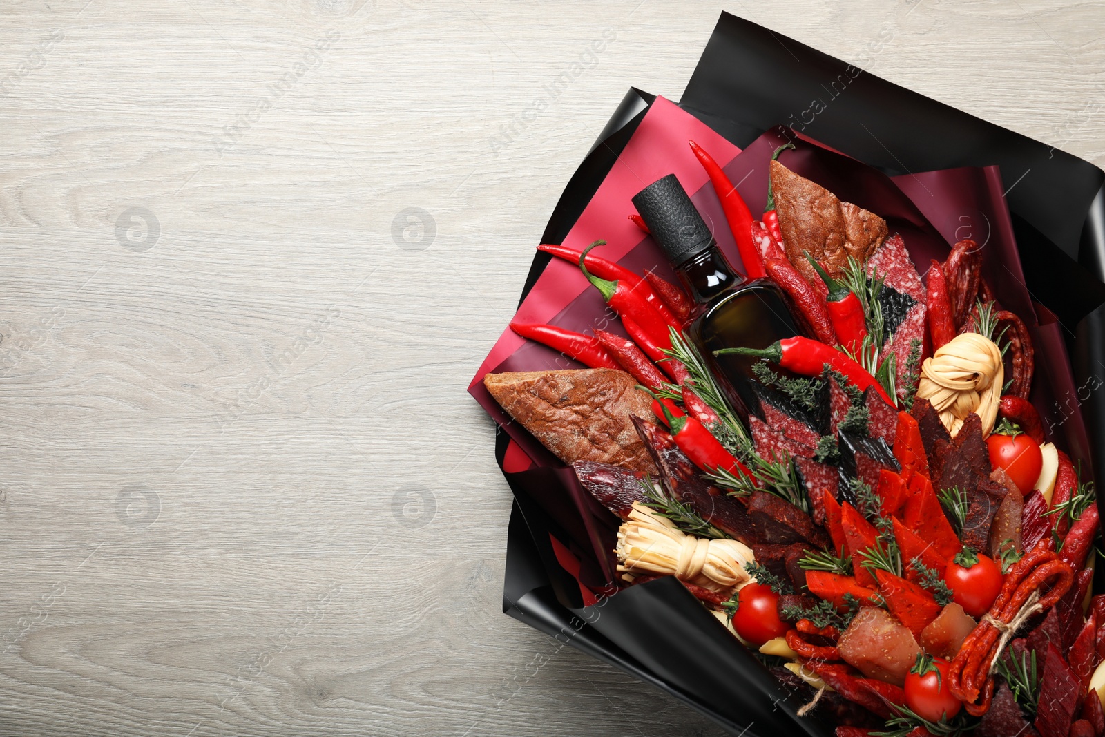 Photo of Beautiful edible bouquet with meat, cheese and vegetables on wooden table, top view. Space for text