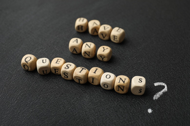 Photo of Phrase Have Any Questions made of wooden cubes on black background