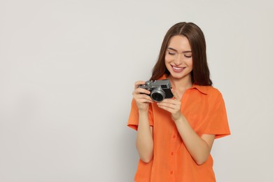 Photo of Young woman with camera on white background, space for text. Interesting hobby