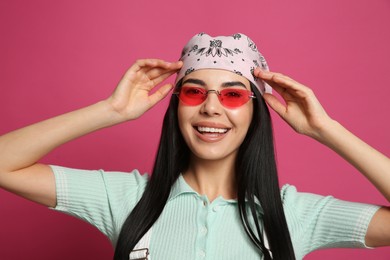 Photo of Young woman wearing stylish bandana and sunglasses on pink background