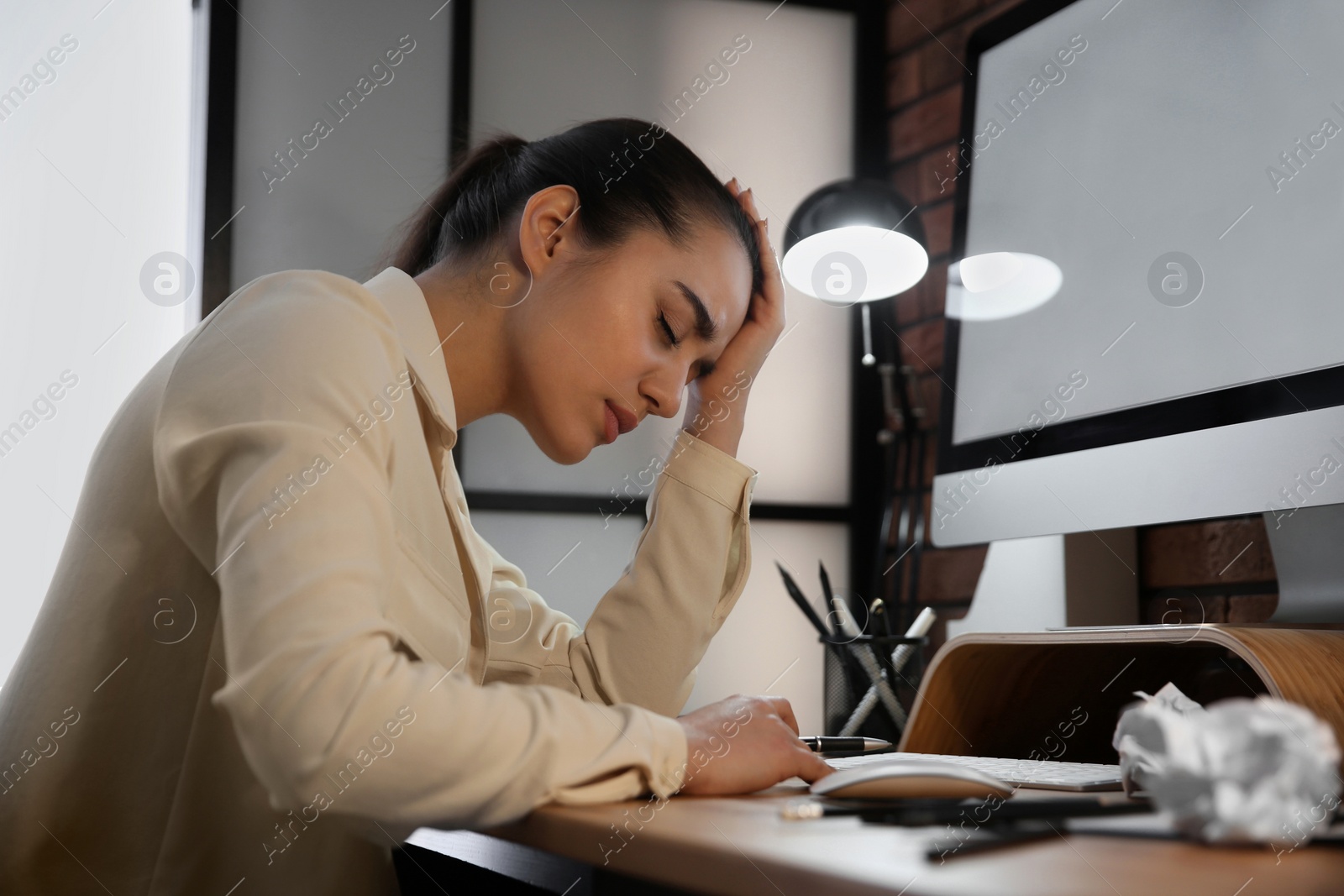 Photo of Stressed and tired young woman at workplace