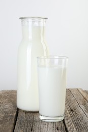 Carafe and glass of fresh milk on wooden table