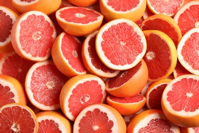 Photo of Many sliced fresh grapefruits as background, top view