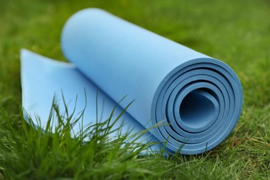 Photo of Bright karemat or fitness mat in fresh green grass outdoors, closeup