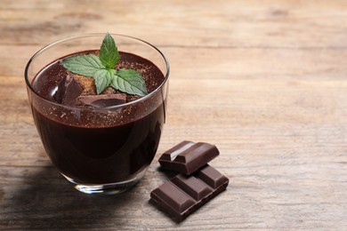 Photo of Glass cup of delicious hot chocolate with fresh mint on wooden table. Space for text