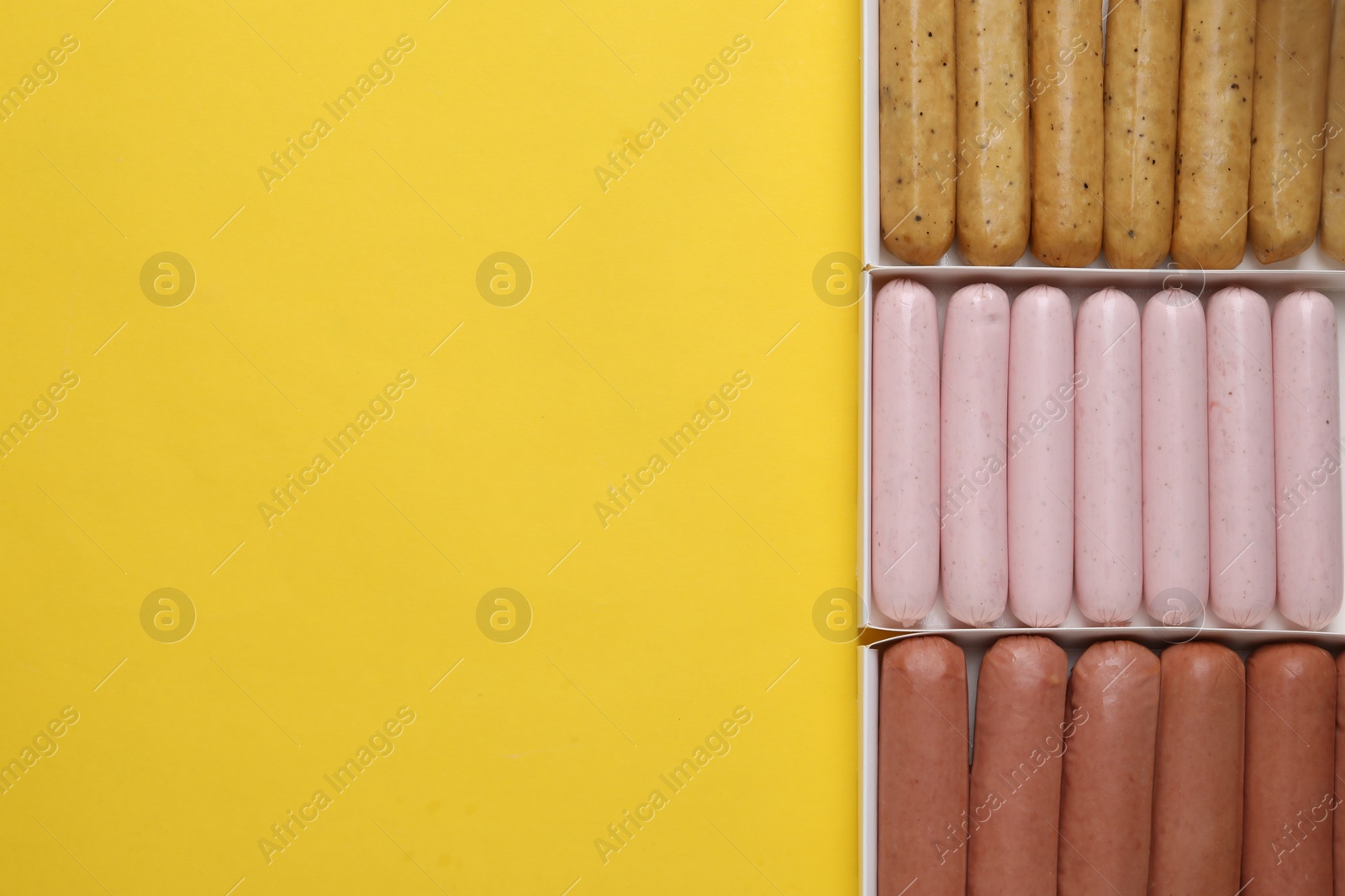 Photo of Different vegan sausages on yellow background, flat lay. Space for text