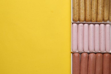 Photo of Different vegan sausages on yellow background, flat lay. Space for text