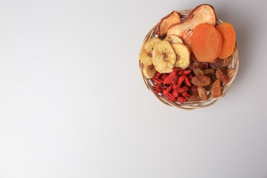 Photo of Wicker basket with different dried fruits on white background, top view. Space for text