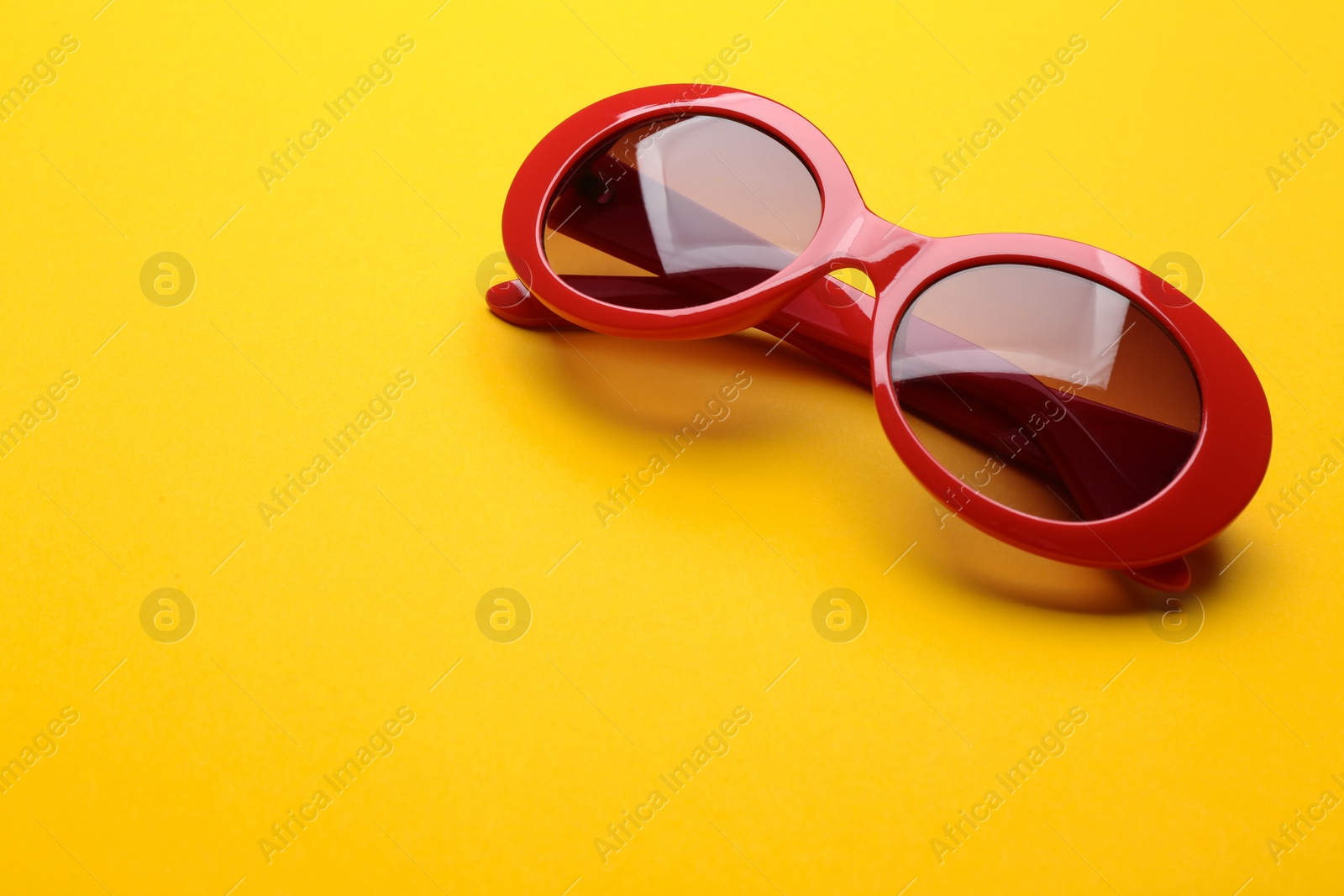 Photo of Stylish sunglasses on yellow background, space for text. Fashionable accessory