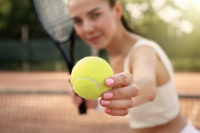 Photo of Young woman playing tennis at court, focus on ball