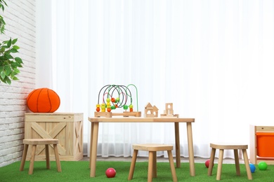 Photo of Stylish playroom interior with toys and modern wooden furniture