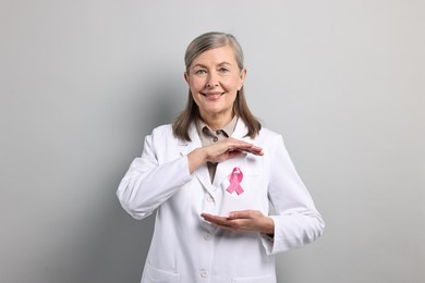 Photo of Mammologist with pink ribbon on gray background. Breast cancer awareness