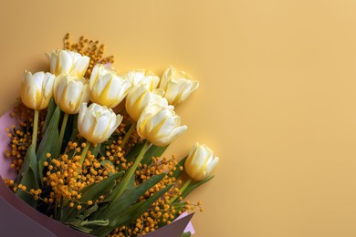 Bouquet with beautiful tulips and mimosa flowers on yellow background, top view. Space for text