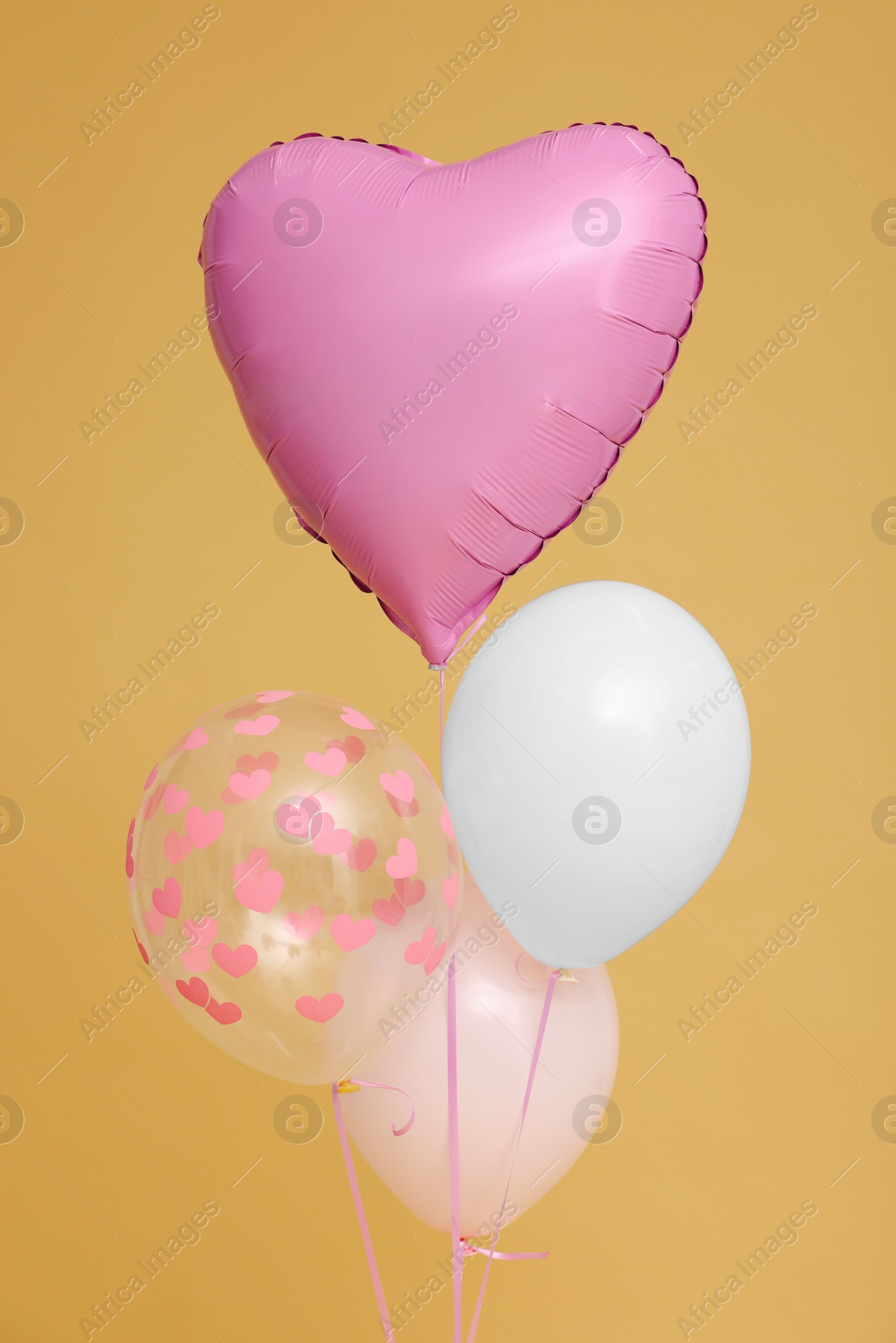 Photo of Bunch of heart and round shaped balloons for birthday party on beige background