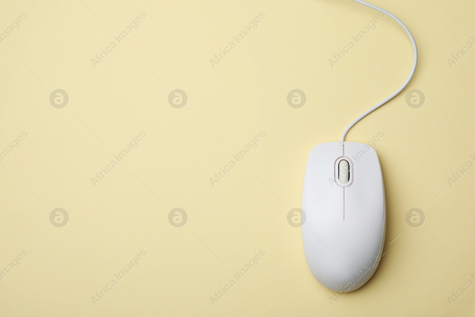 Photo of Wired computer mouse on yellow background, top view. Space for text