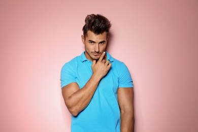 Young man with trendy hairstyle posing on color background