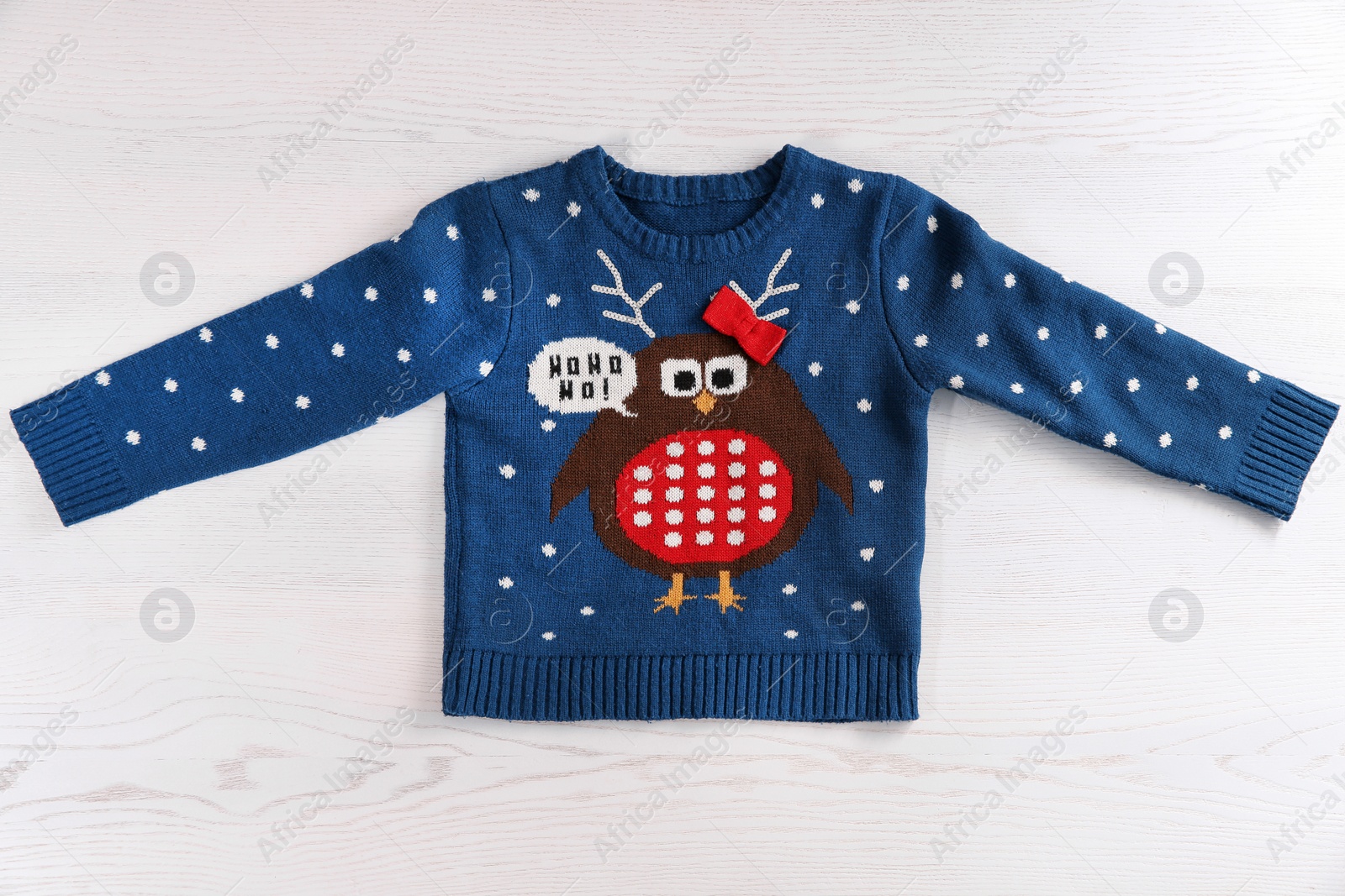 Photo of Christmas sweater with pattern on wooden background, top view