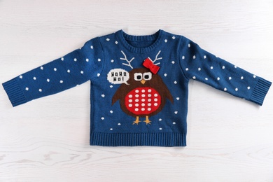 Photo of Christmas sweater with pattern on wooden background, top view