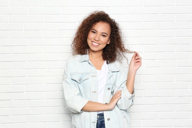 Young African-American woman with beautiful face near white brick wall