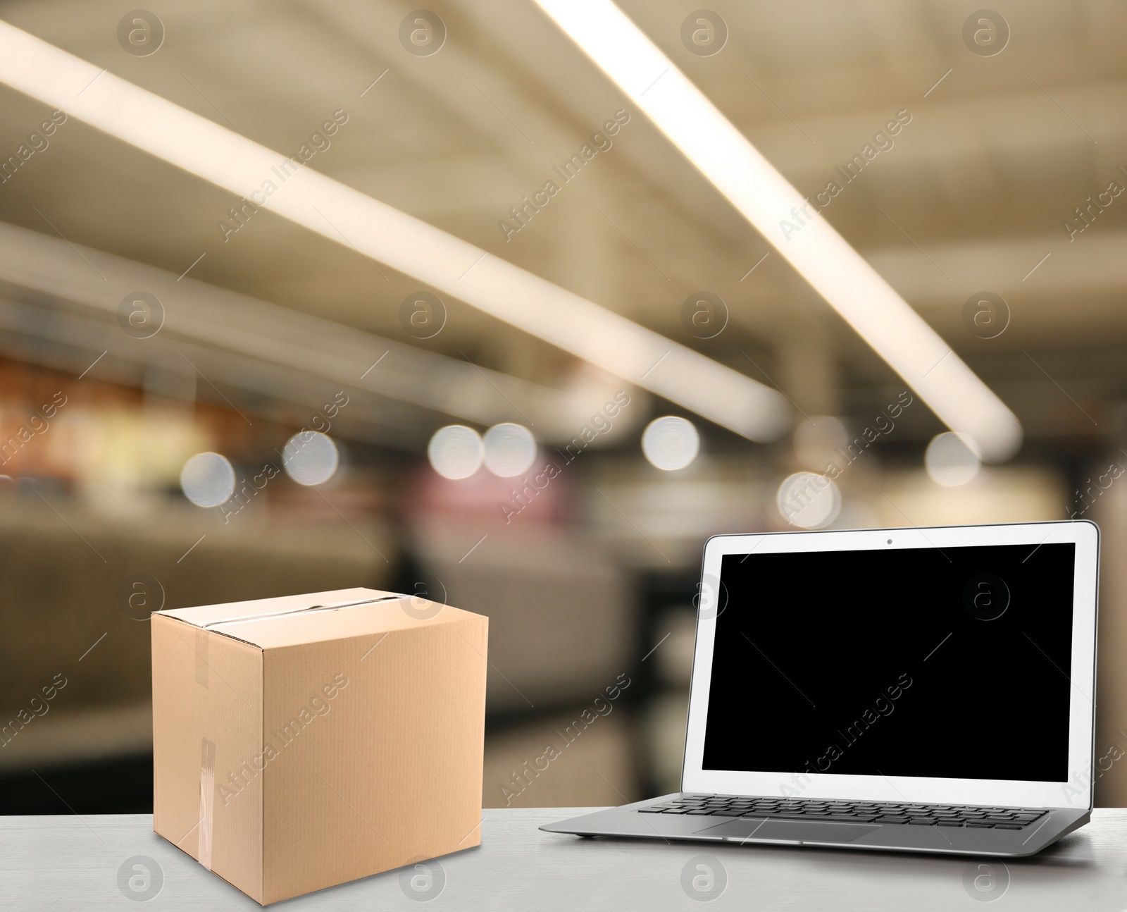 Image of Online selling. Laptop and parcel on table in store