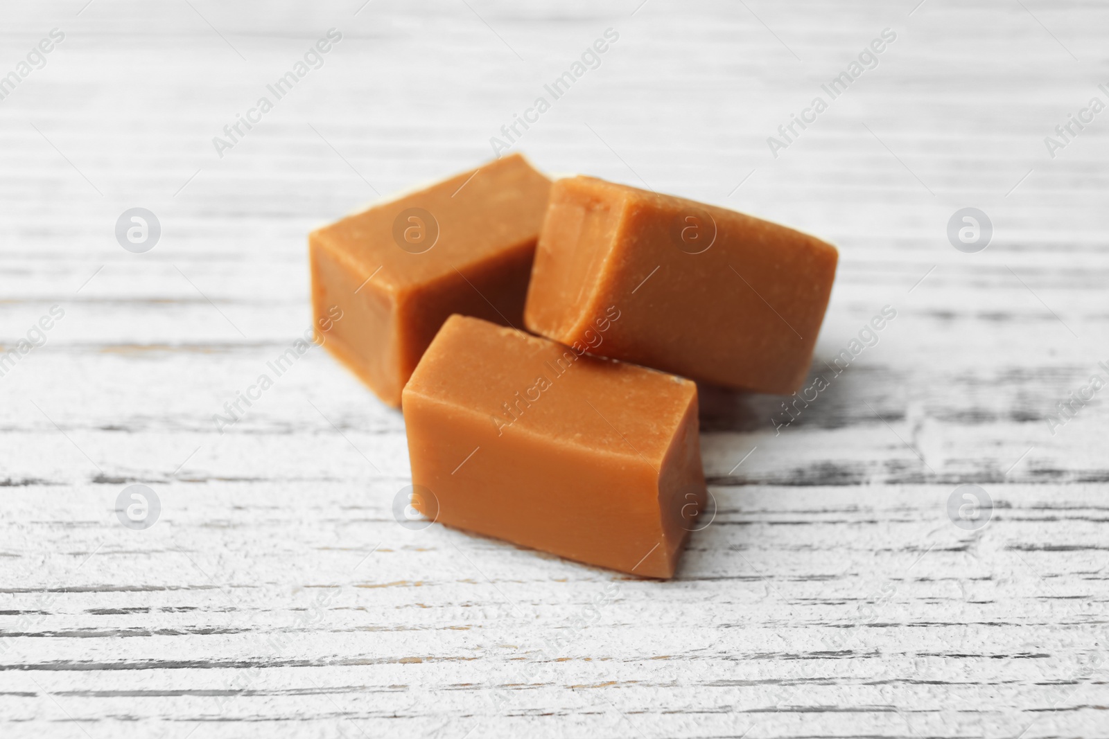 Photo of Delicious caramel candies on wooden background