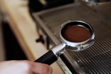 Photo of Barista holding portafilter with ground coffee, closeup. Space for text