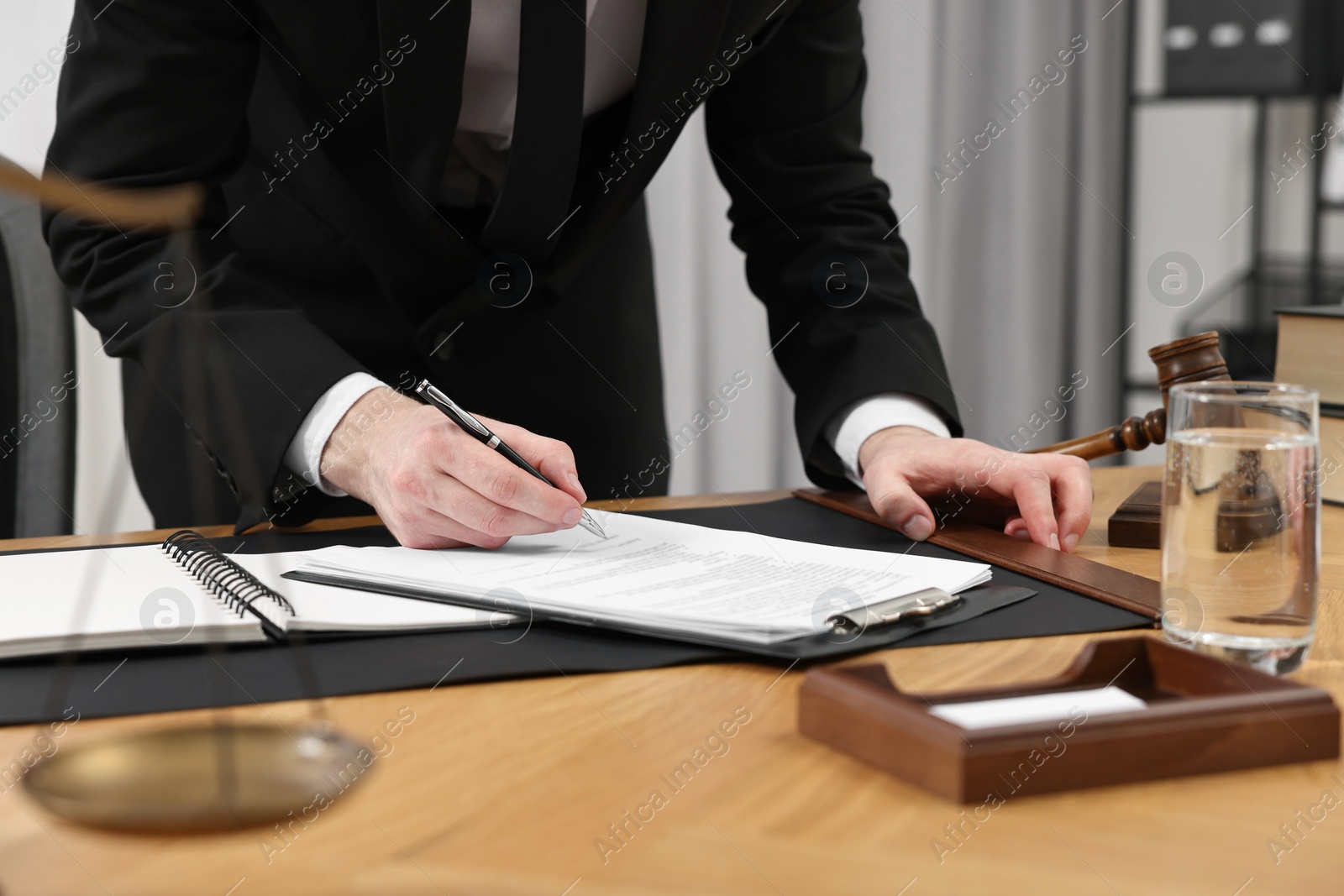 Photo of Lawyer working with documents at wooden table indoors, closeup