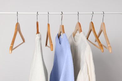 Photo of Rack with different warm sweaters on light background