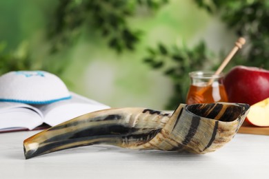 Shofar and other Rosh Hashanah holiday attributes on white wooden table outdoors