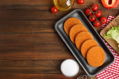 Photo of Uncooked breaded cutlets on wooden table, flat lay with space for text. Freshly frozen semi-finished product