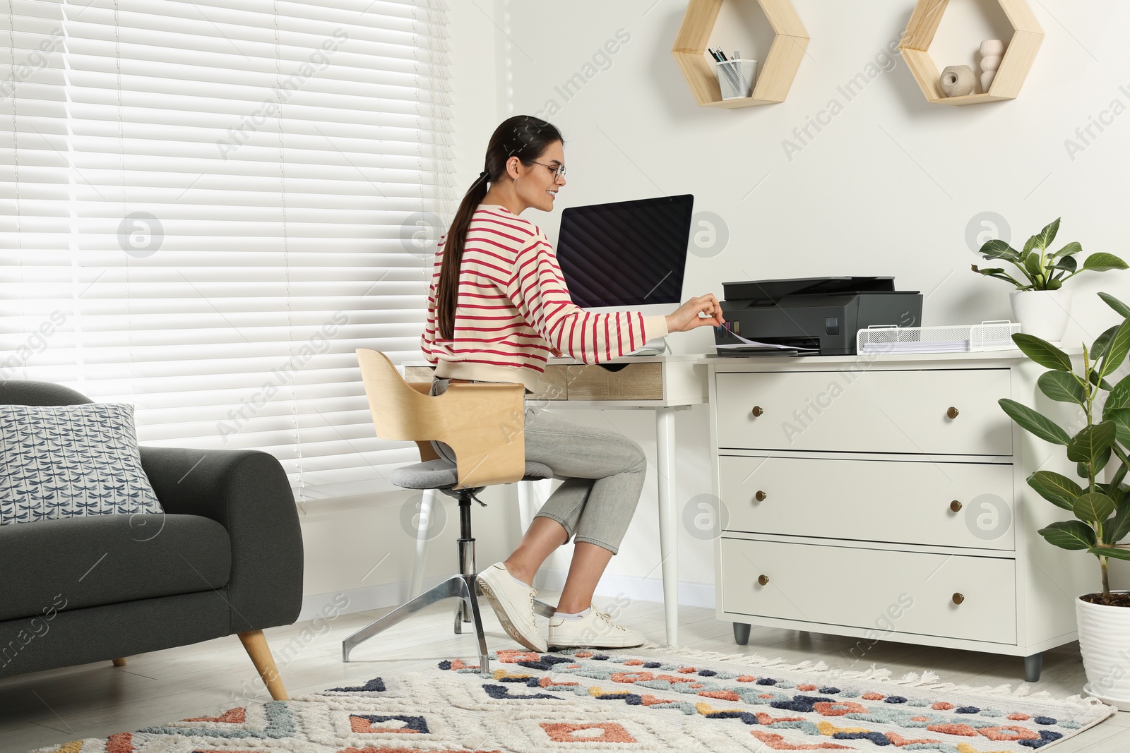 Photo of Woman using modern printer at workplace indoors