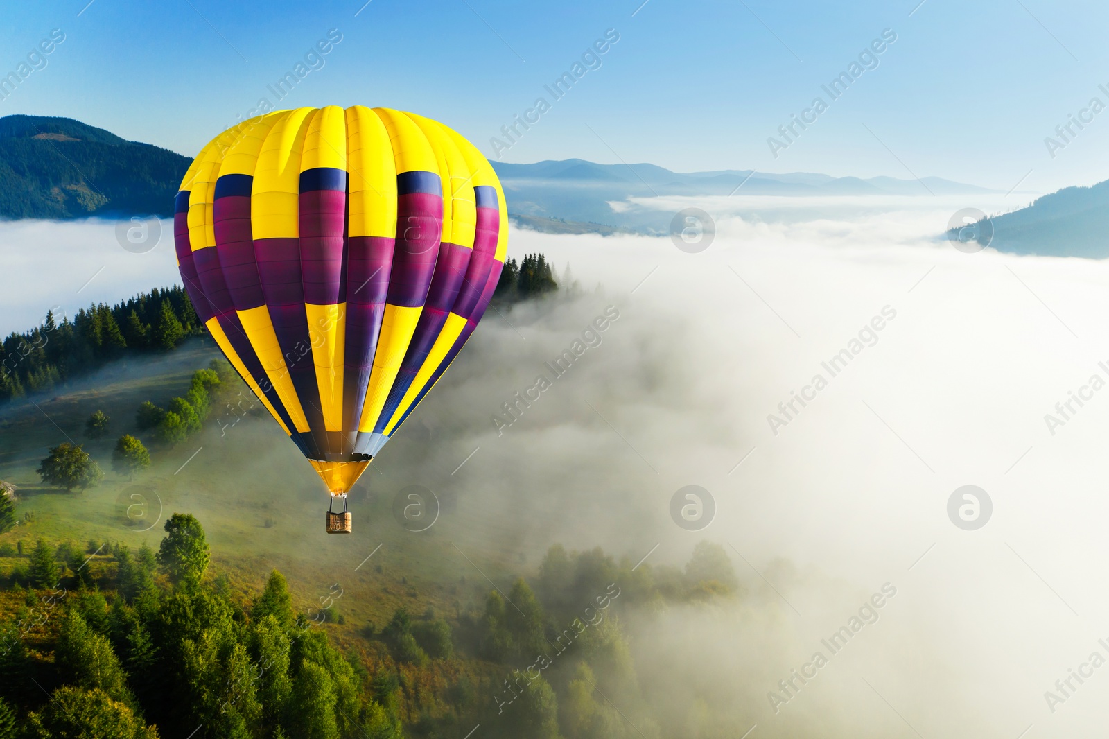 Image of Hot air balloon flying over foggy mountains